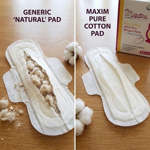 Side-by-side comparison photo on a wooden table: left shows a torn-open ‘generic “natural” pad’ with clumpy, brownish filler exposed and loose cotton pieces around it; right shows a clean, intact ‘Maxim pure cotton pad’ with smooth layered structure. A Ma